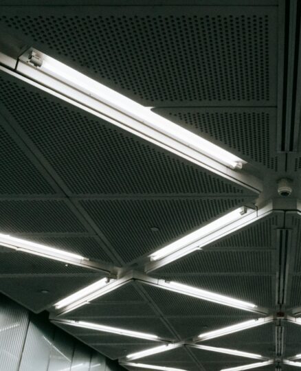 A modern indoor ceiling featuring geometric patterns and bright LED lighting.